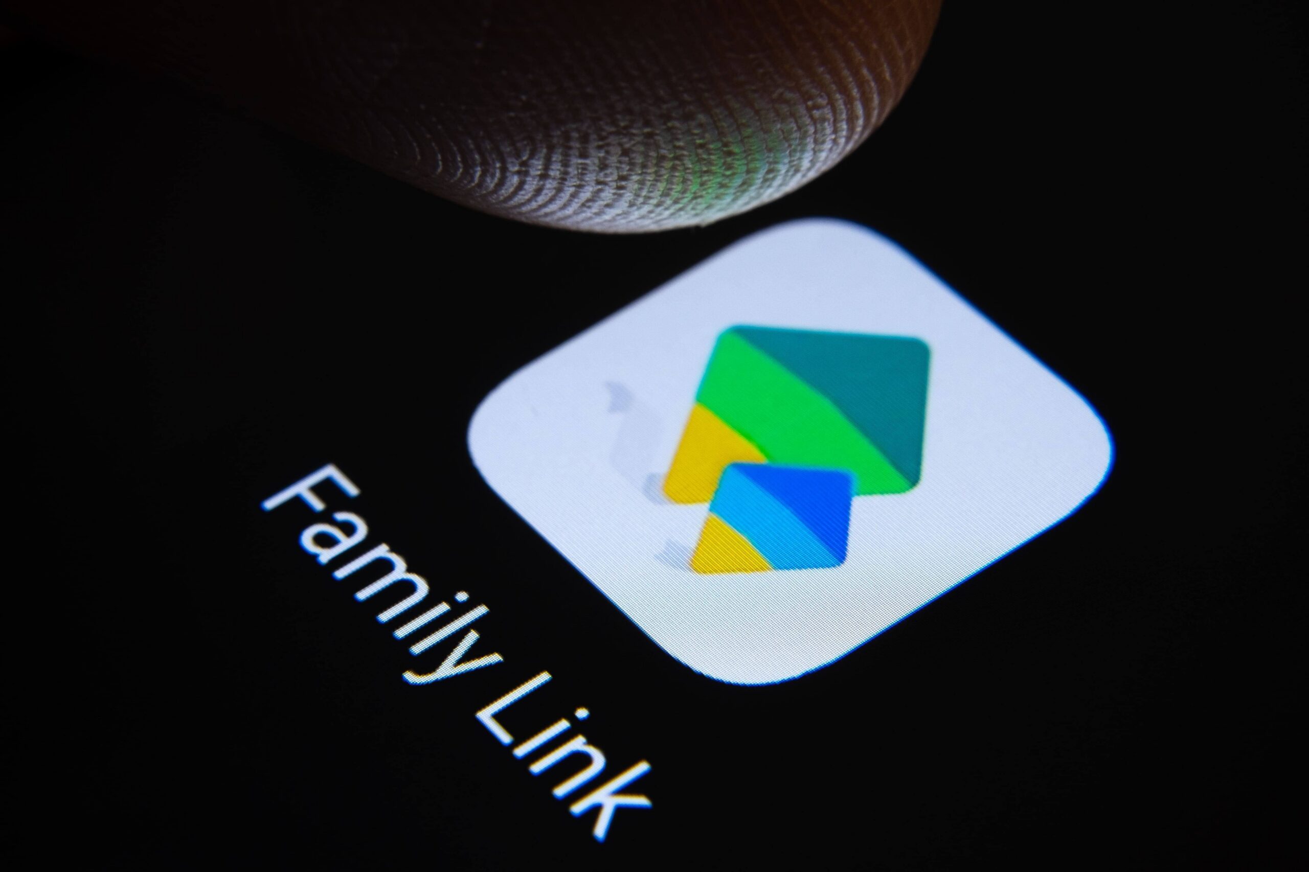 Parent consultant l'application Family Link sur son smartphone pour régler le temps d'écran de son enfant