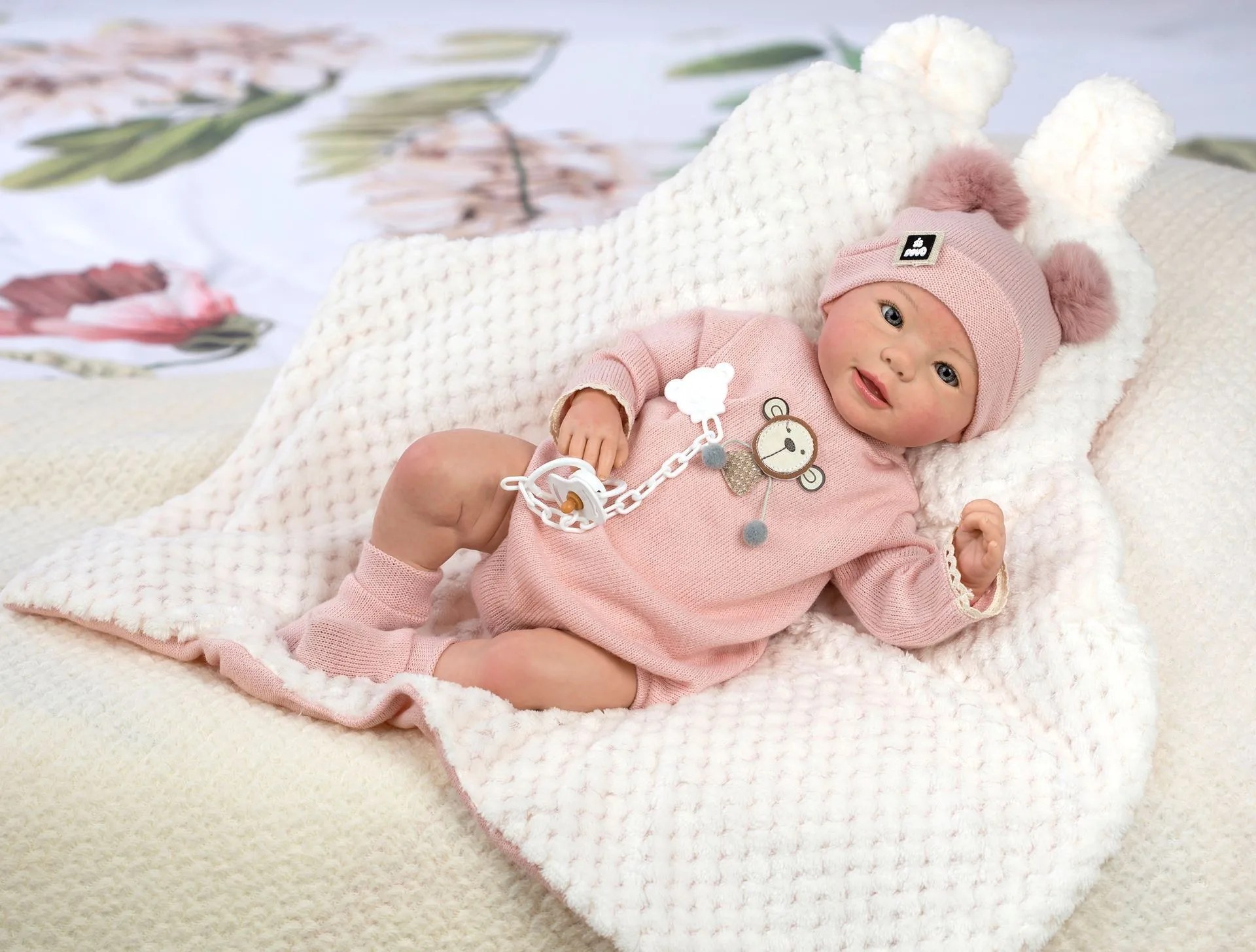 Poupée reborn hyperréaliste aux yeux fermés, habillée en tenue de nouveau-né et posée sur une couverture