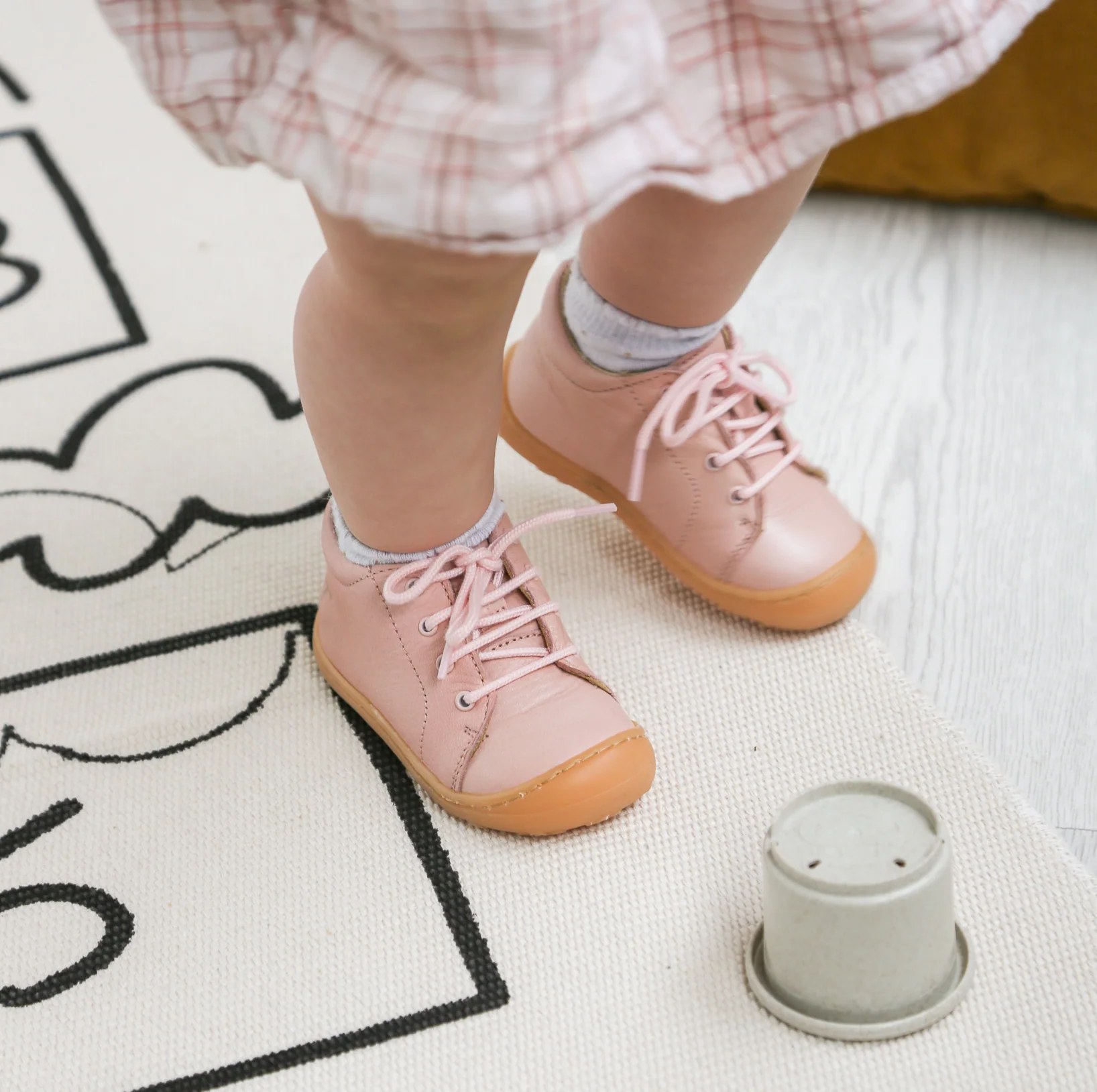 Paire de chaussures souples en cuir pour bébé posée au sol